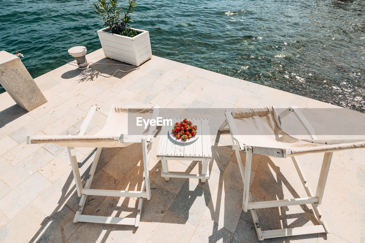 HIGH ANGLE VIEW OF CHAIRS AND TABLE AT SWIMMING POOL