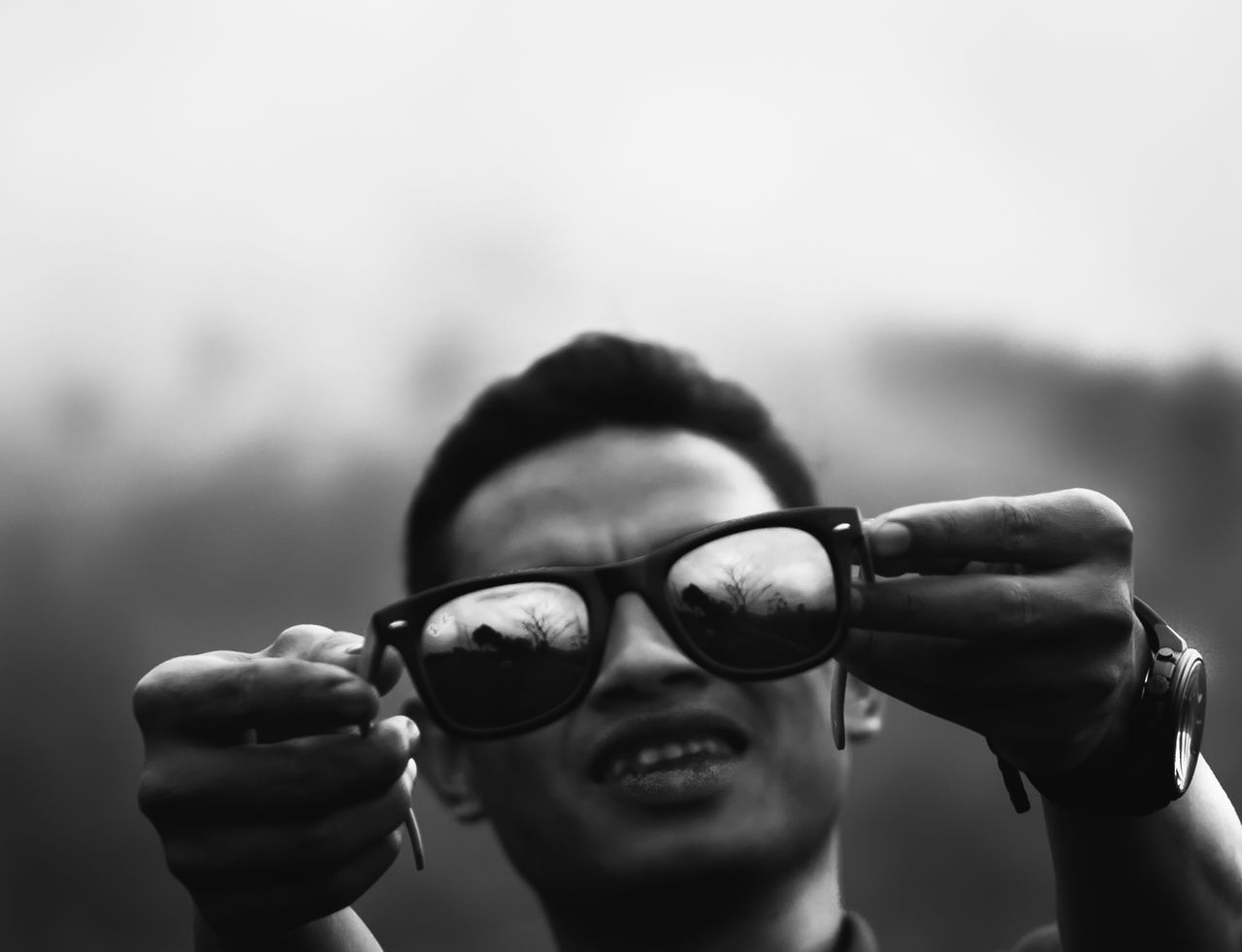 Close-up of man holding reflective sunglasses