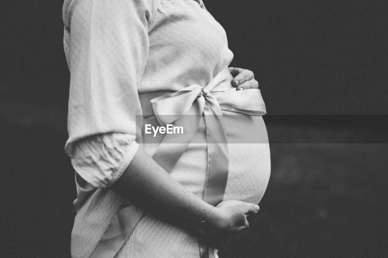 Close-up of pregnant woman standing on field