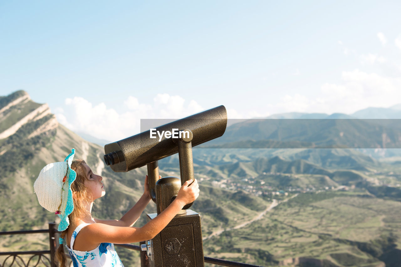 rear view of woman drinking water from mountains against sky