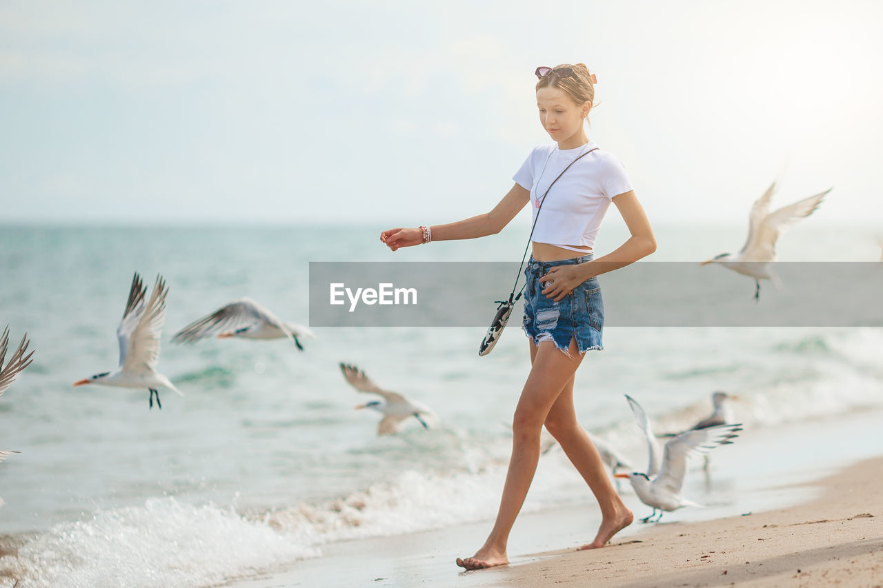 full length of woman standing on shore at beach against sky