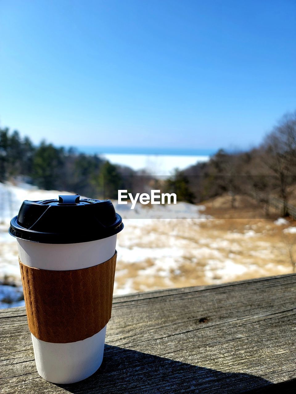 CLOSE-UP OF COFFEE CUP ON TABLE AGAINST CLEAR SKY