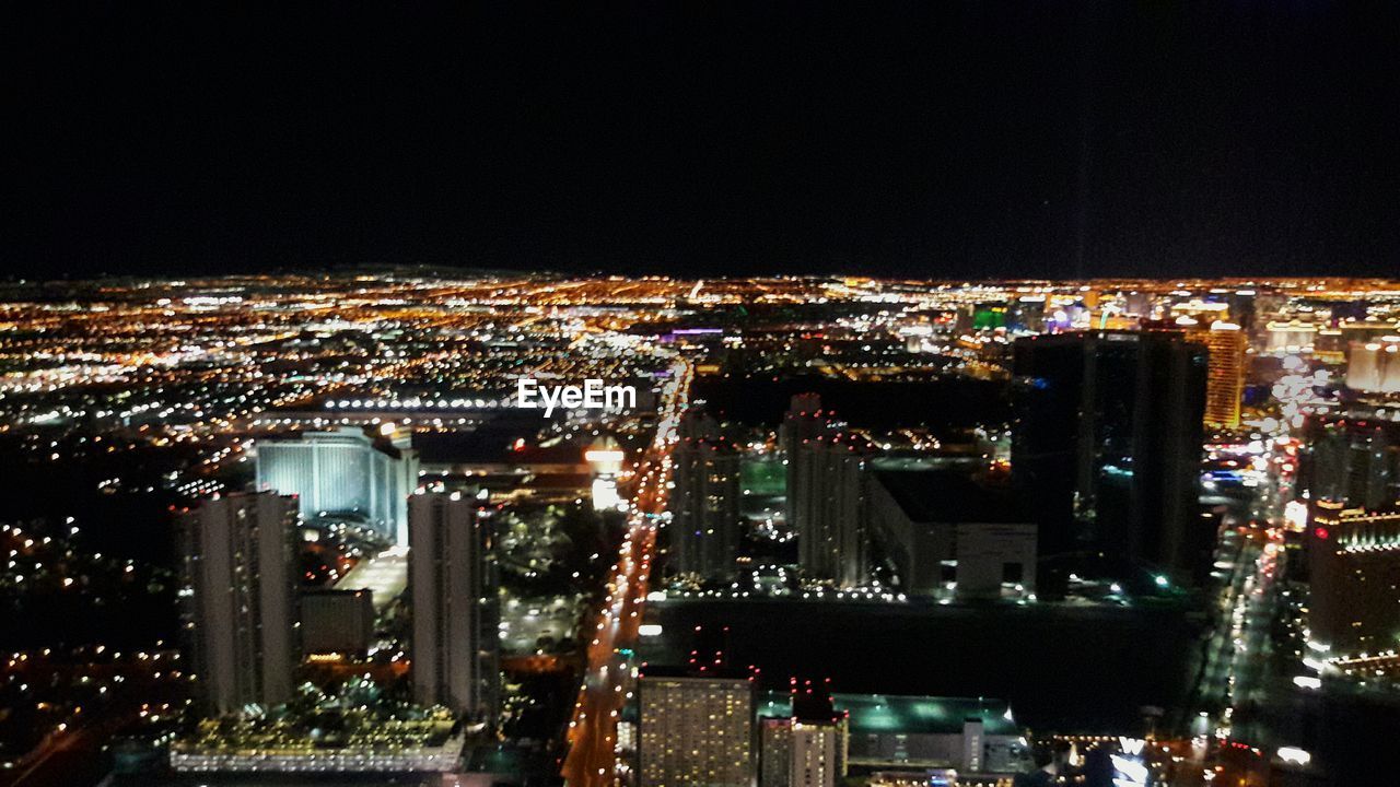 AERIAL VIEW OF ILLUMINATED CITYSCAPE AGAINST SKY