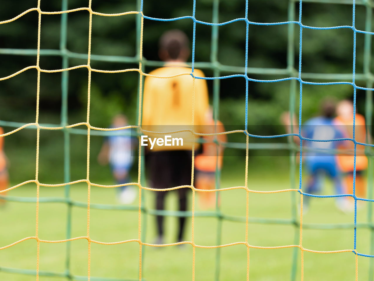 View through soccer gate net. g
oalkeeper slowly backs up during the opponents attack. abstract view