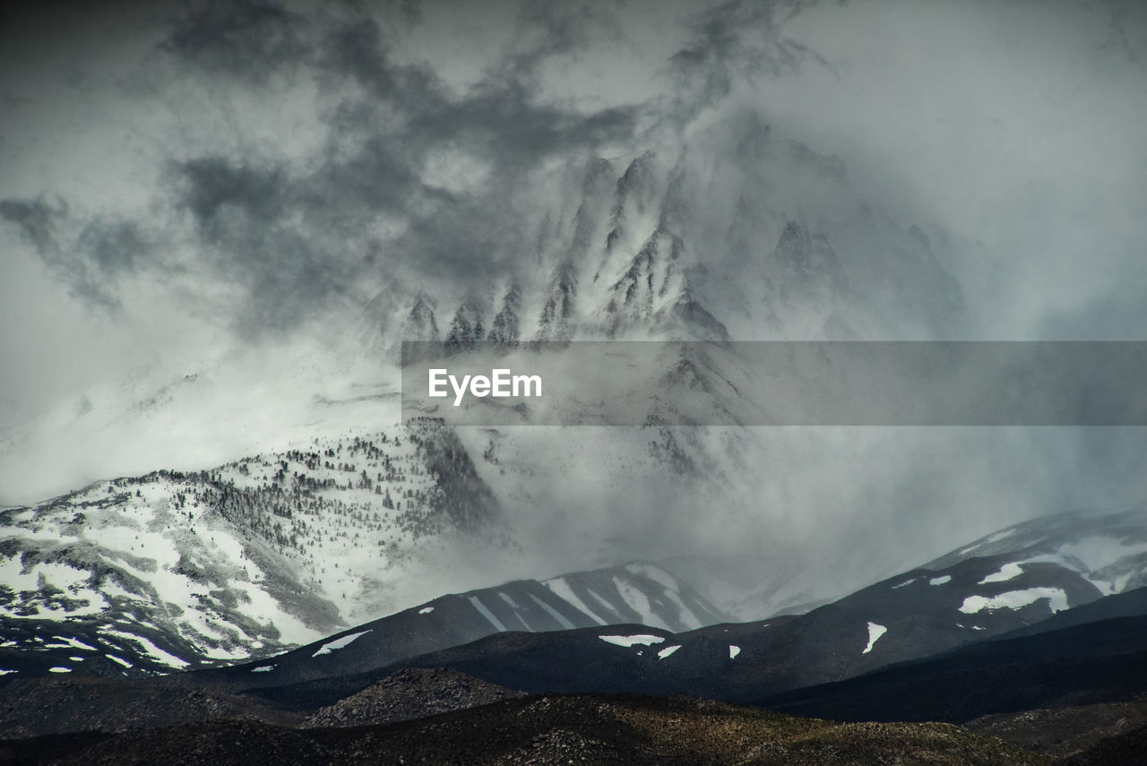 Snowcapped mountains against sky during foggy weather