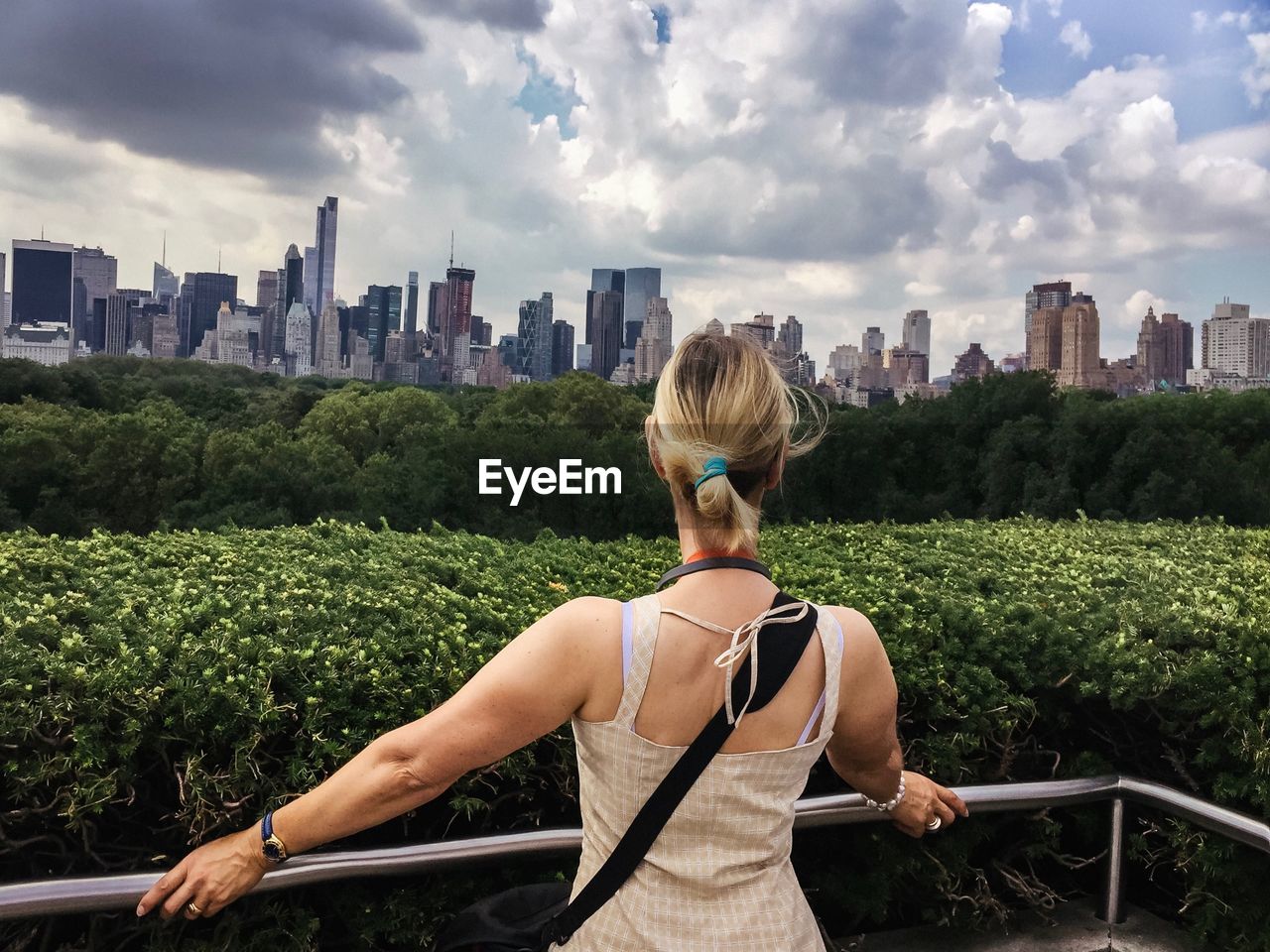 Rear view of woman looking at cityscape against sky