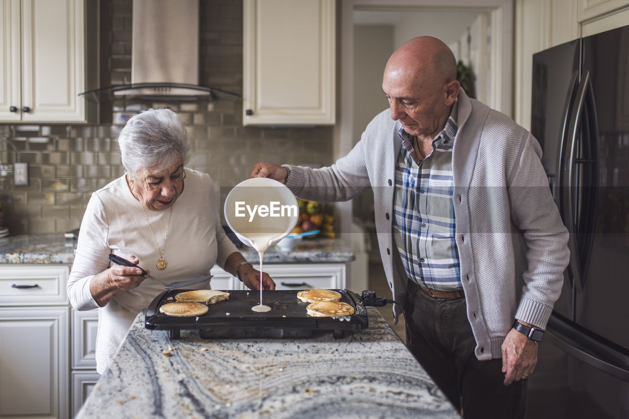 Great grandma cooking pancakes with her adult son