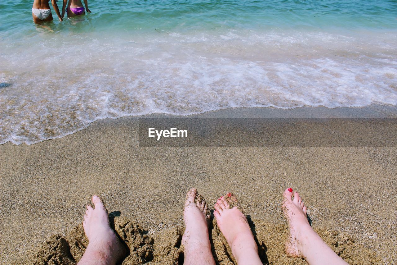 LOW SECTION OF PERSON ON SHORE AT BEACH