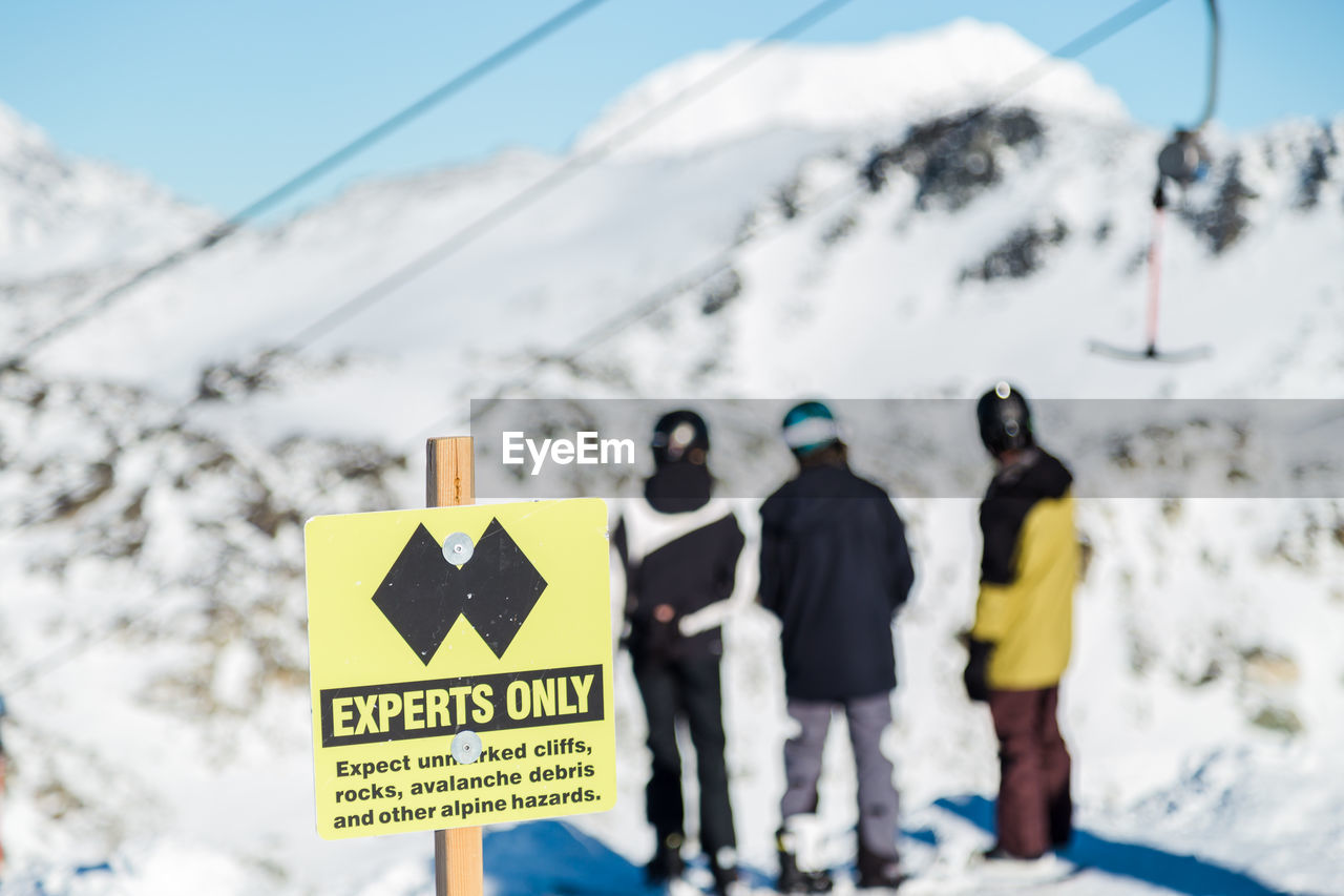 Rear view of people standing on snowcapped mountain