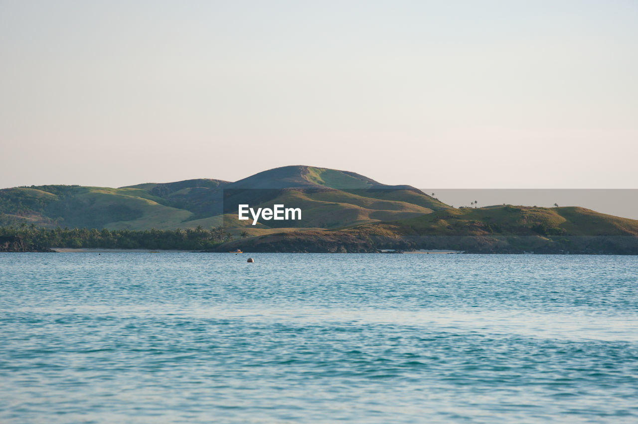 SCENIC VIEW OF SEA AND MOUNTAIN AGAINST CLEAR SKY