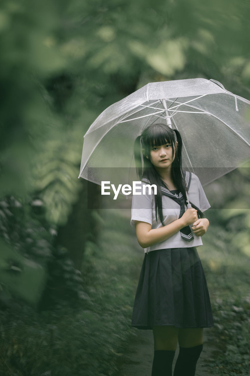 Full length of woman with umbrella standing in rain