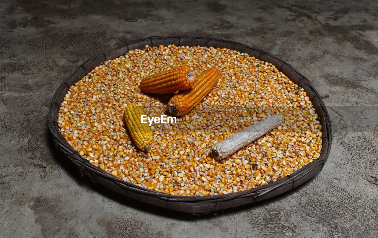 High angle view of corn and kernels in plate on floor