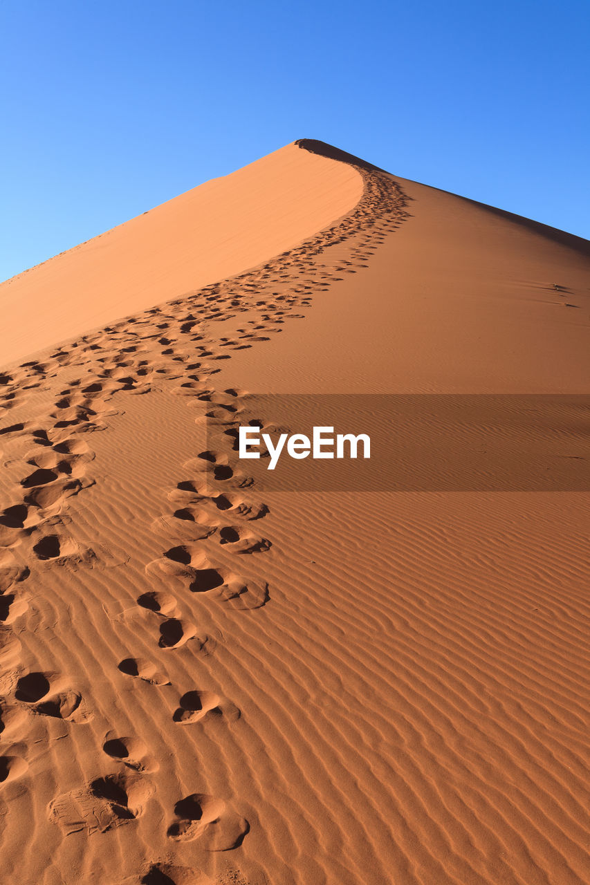 Sand dunes in desert against clear blue sky