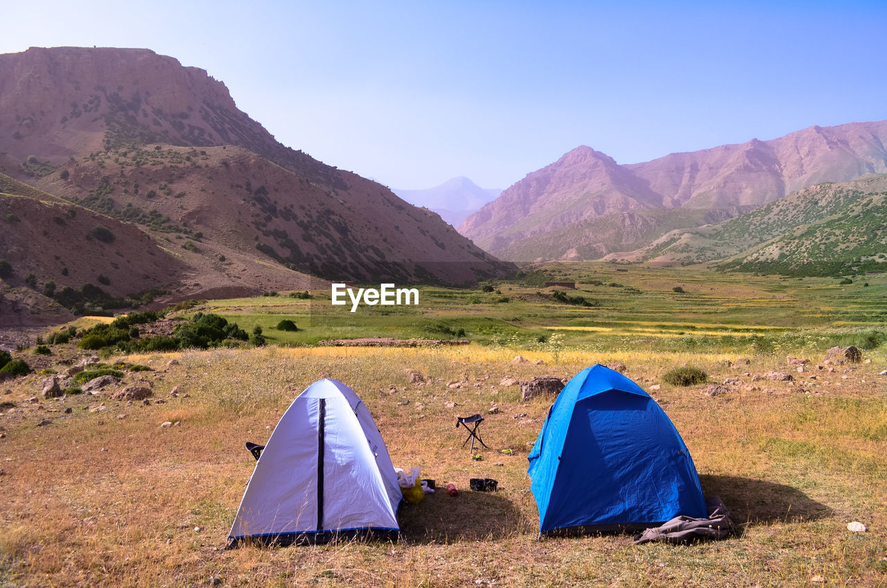 TENT ON FIELD AGAINST MOUNTAINS