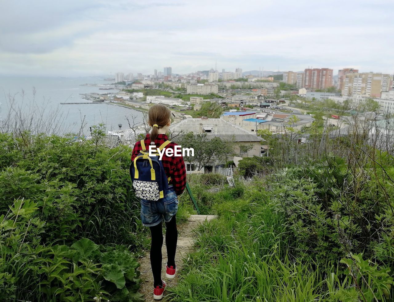 Rear view of girl standing by cityscape against sky