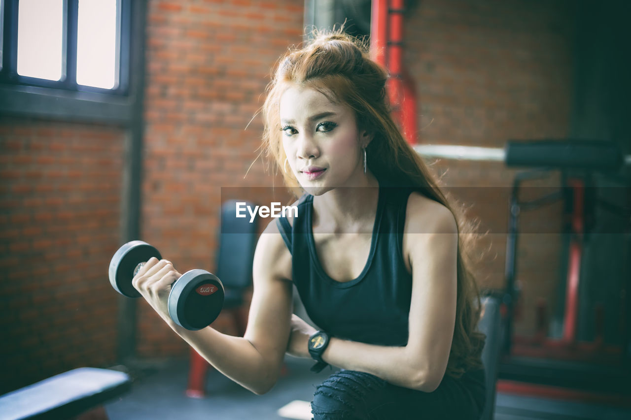 Portrait of smiling young woman exercising in gym