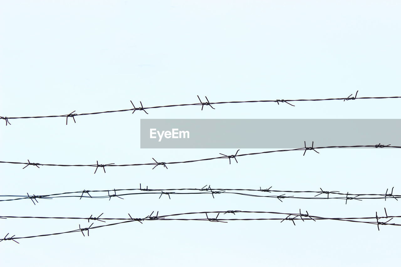 Low angle view of barbed wires against clear sky