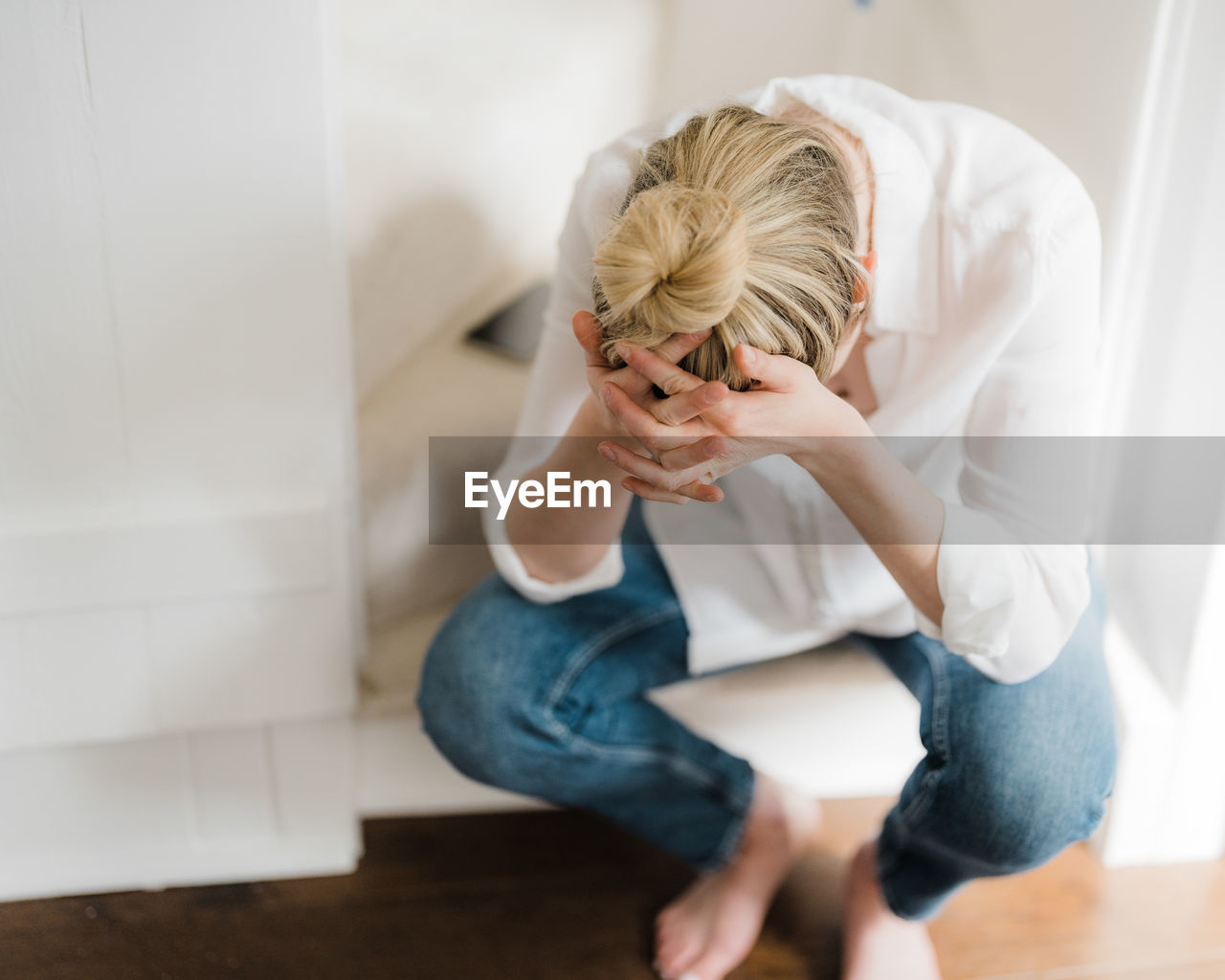 Young woman sitting on the stairs, head in hands.  no face visible.  