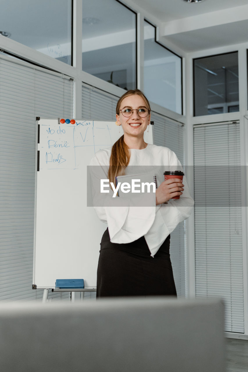 Smiling businesswoman standing by whiteboard in office