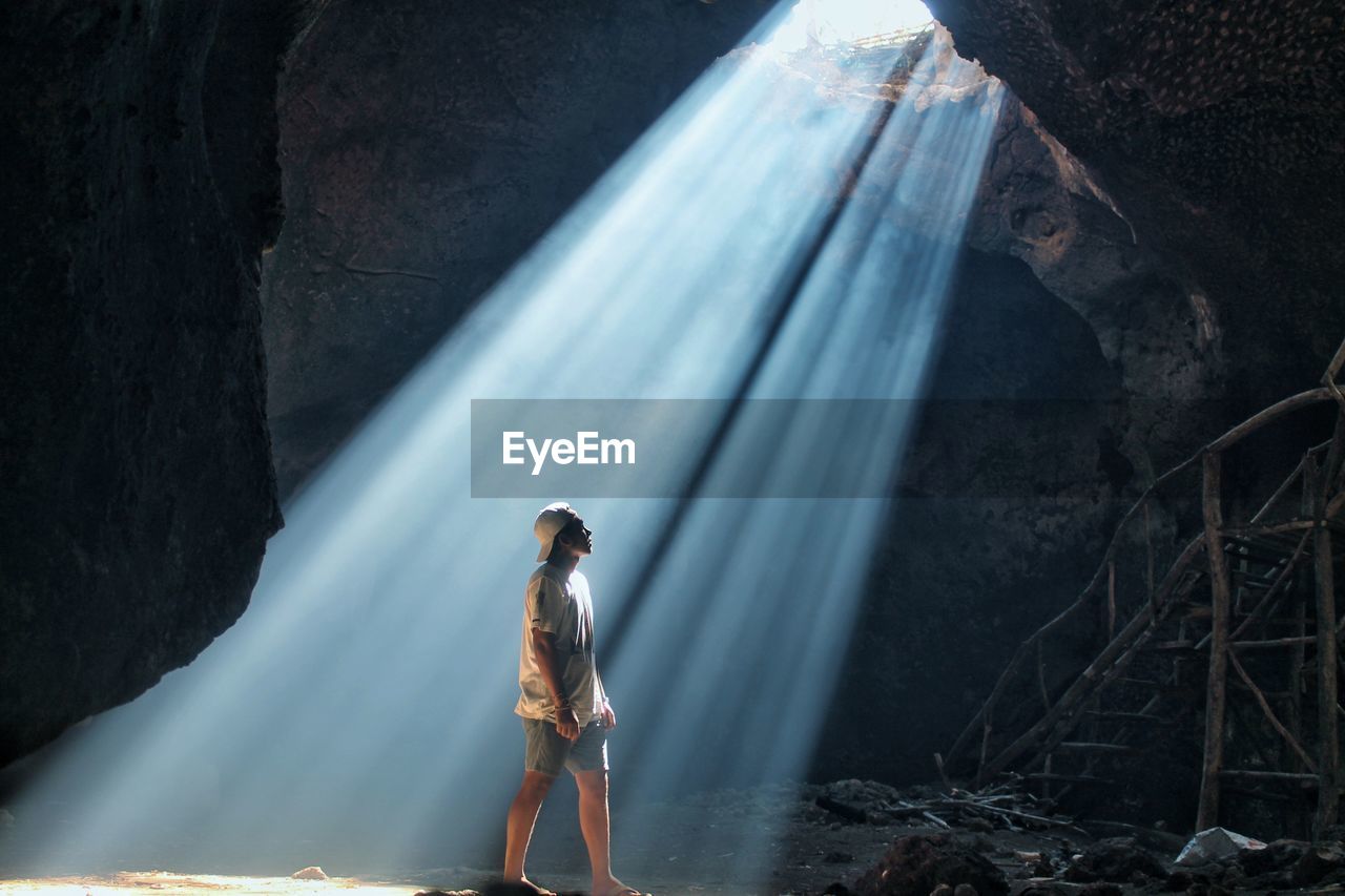 Man standing on rock against sun ray 