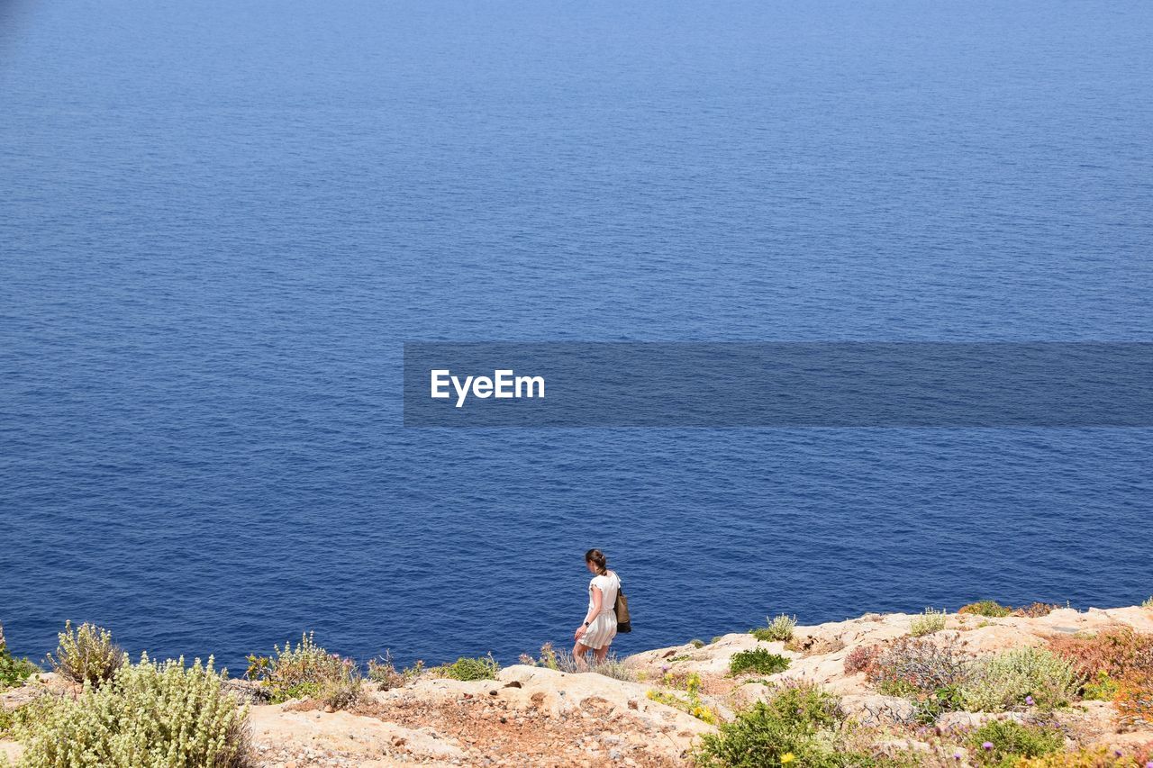 High angle view of woman standing on rocks by sea