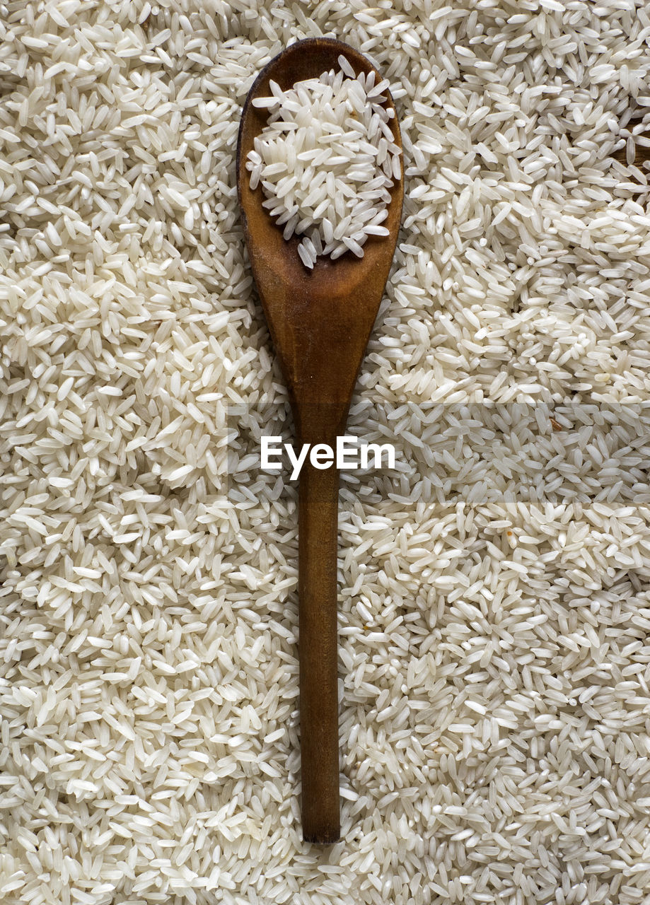 High angle view of wooden spoon on rice grain