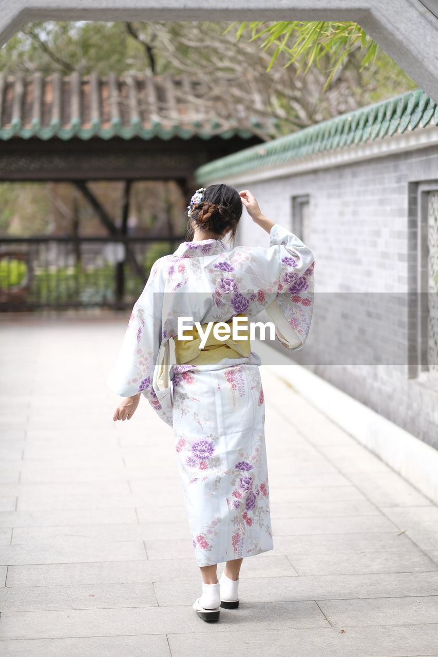 Rear view of woman wearing kimono while walking by house