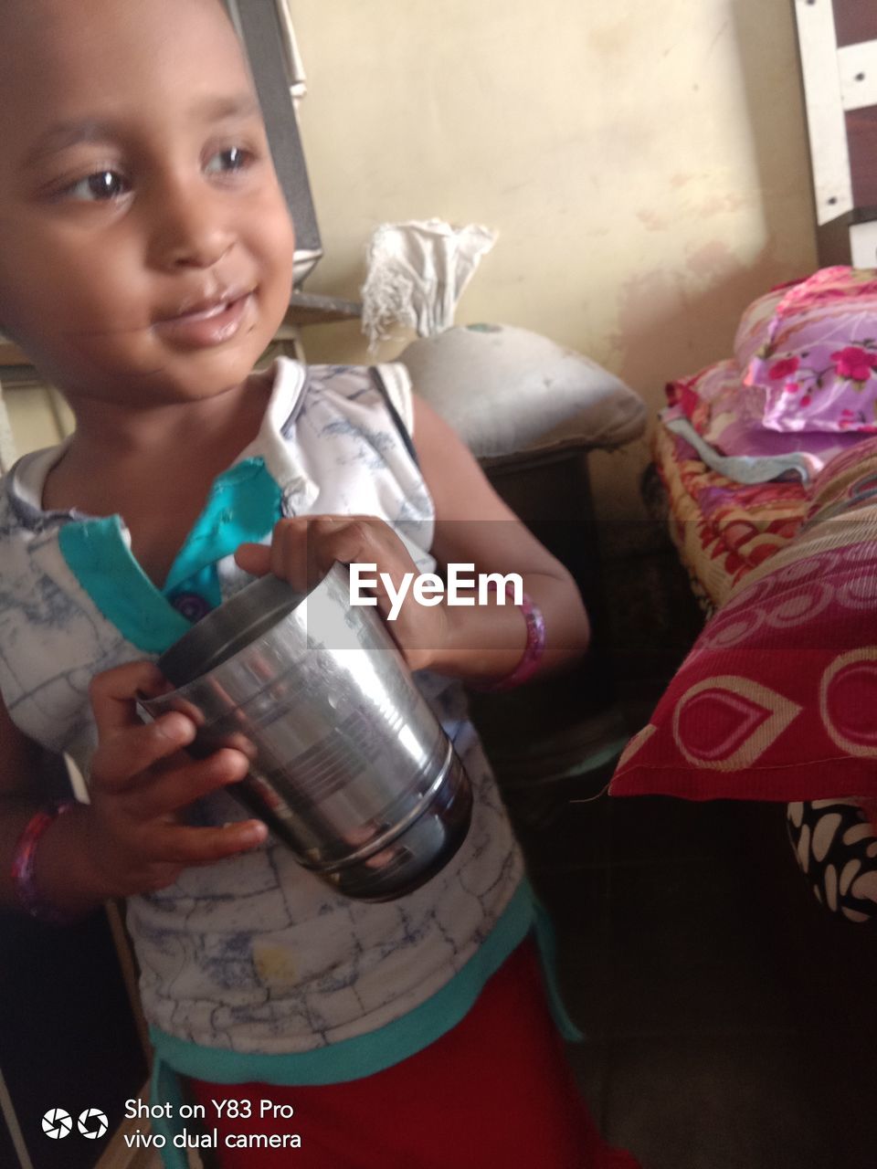 PORTRAIT OF A SMILING GIRL HOLDING CAMERA WHILE SITTING