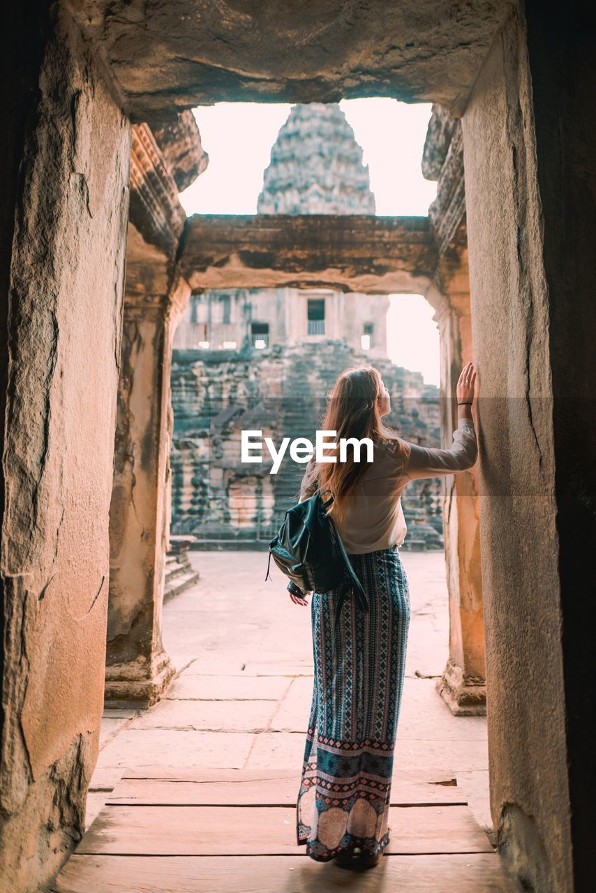 Rear view of woman standing on doorway of ancient temple