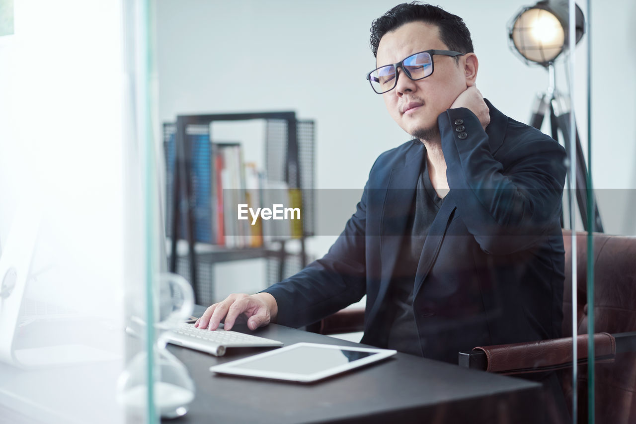 Businessman with neck pain sitting on table