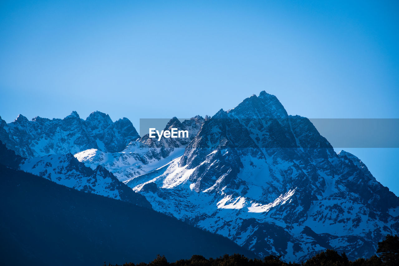 Scenic view of snowcapped mountains against clear blue sky