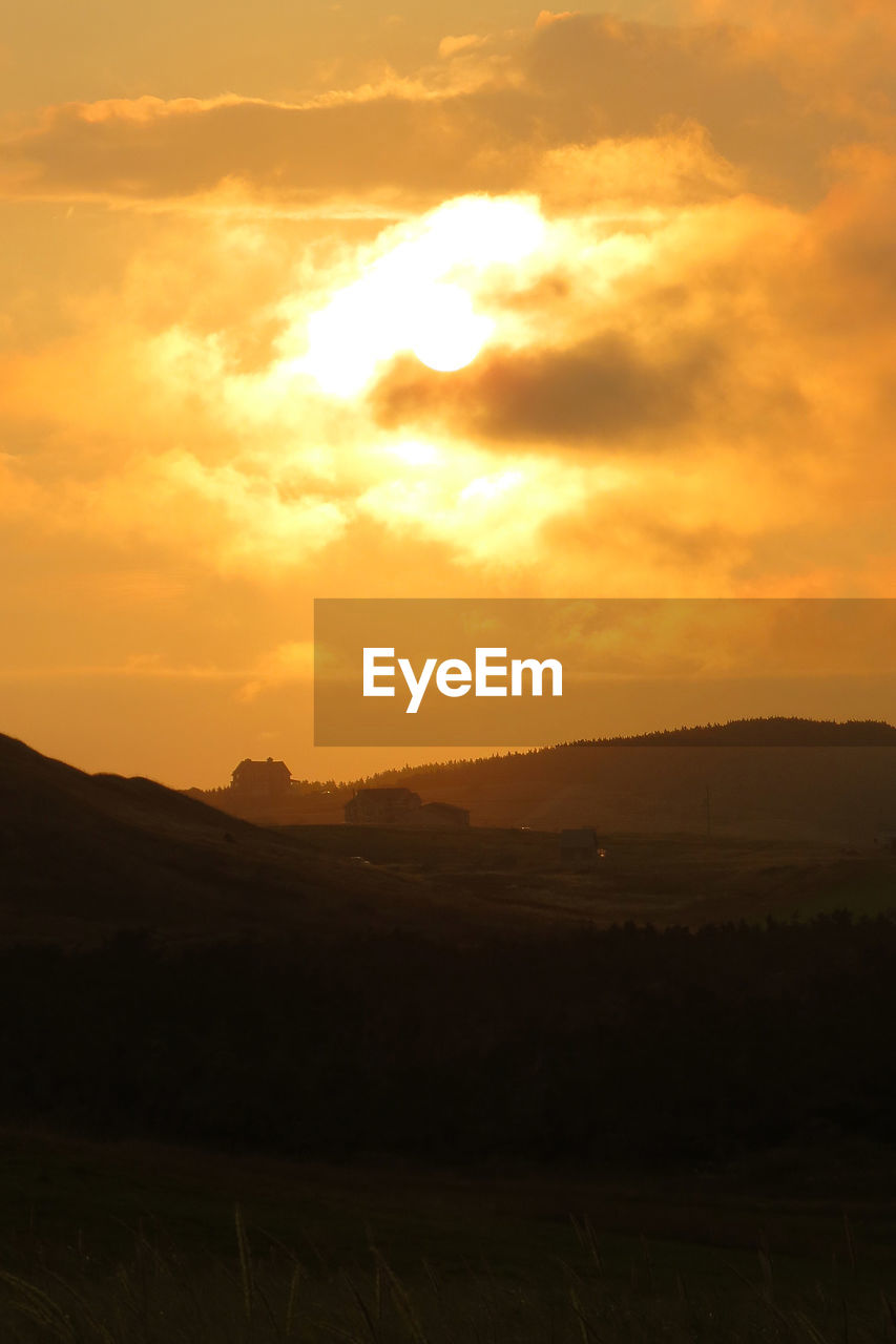 Scenic view of landscape against orange sky during sunset