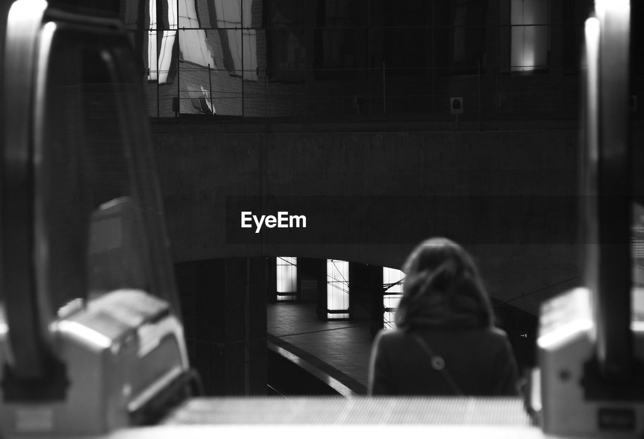 Rear view of woman moving down on escalator at railway station