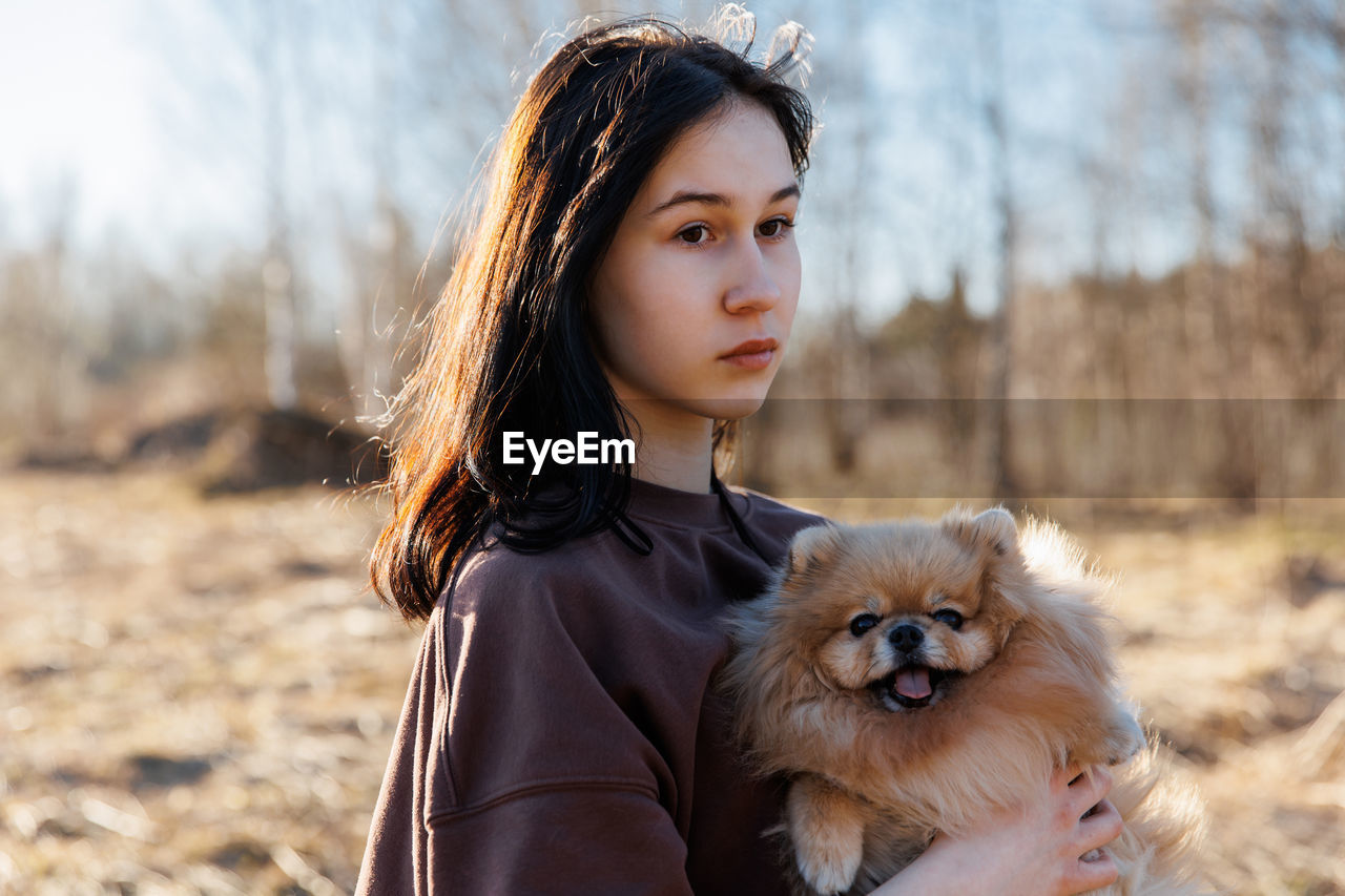 A girl walks with a dog in the park, outdoor recreation with a pet, a portrait with a small puppy