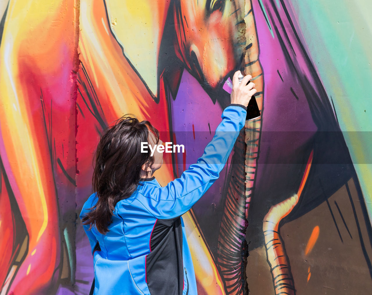 WOMAN STANDING ON MULTI COLORED GRAFFITI