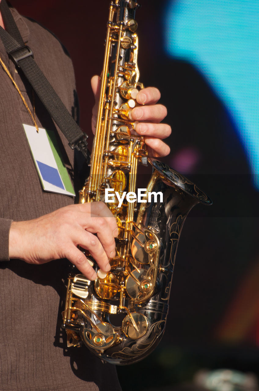 Midsection of man playing saxophone at music concert