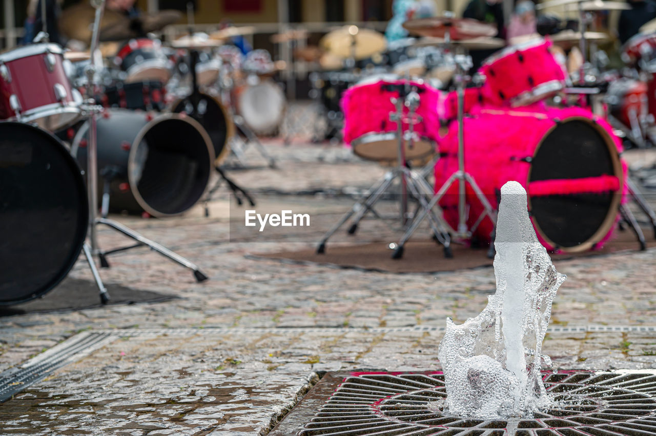 Close-up of a fountain on the background of a defocused paved area with many drum kits