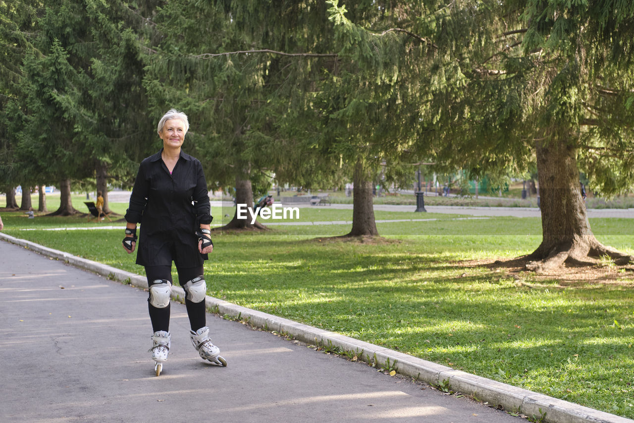 Active senior caucasian woman with gray hair  is roller skating in park. elderly persons concept.