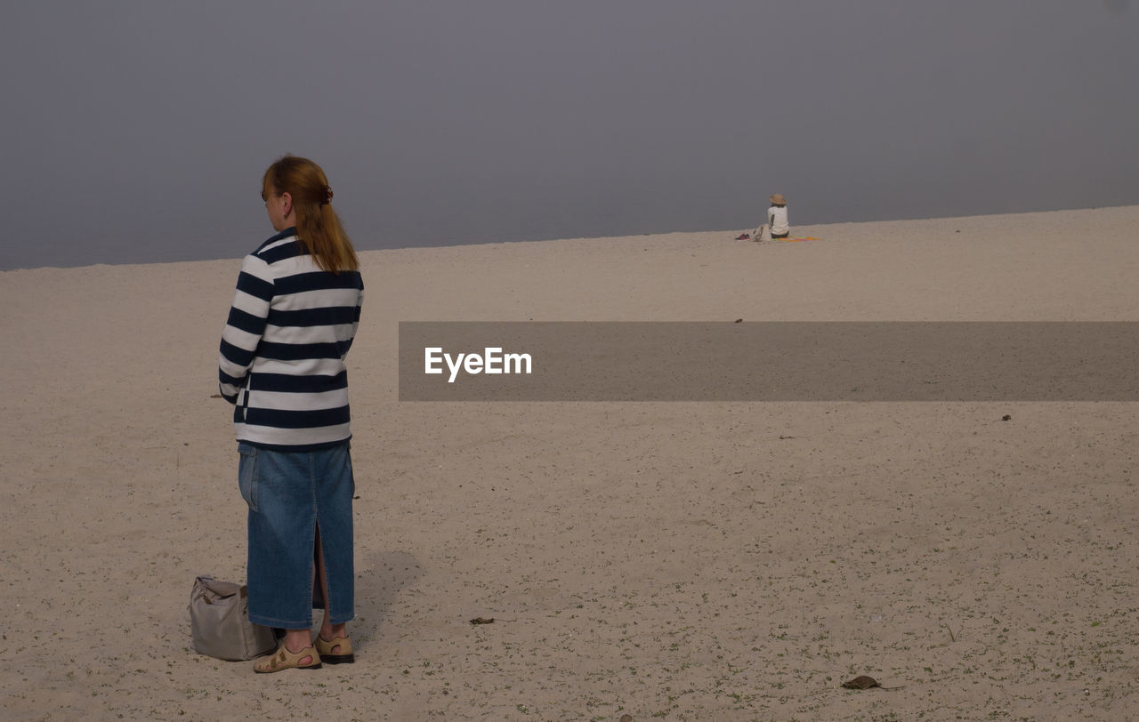 Rear view of woman standing on sand at beach