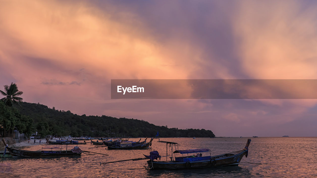 Boats moored on sea against sky during sunset