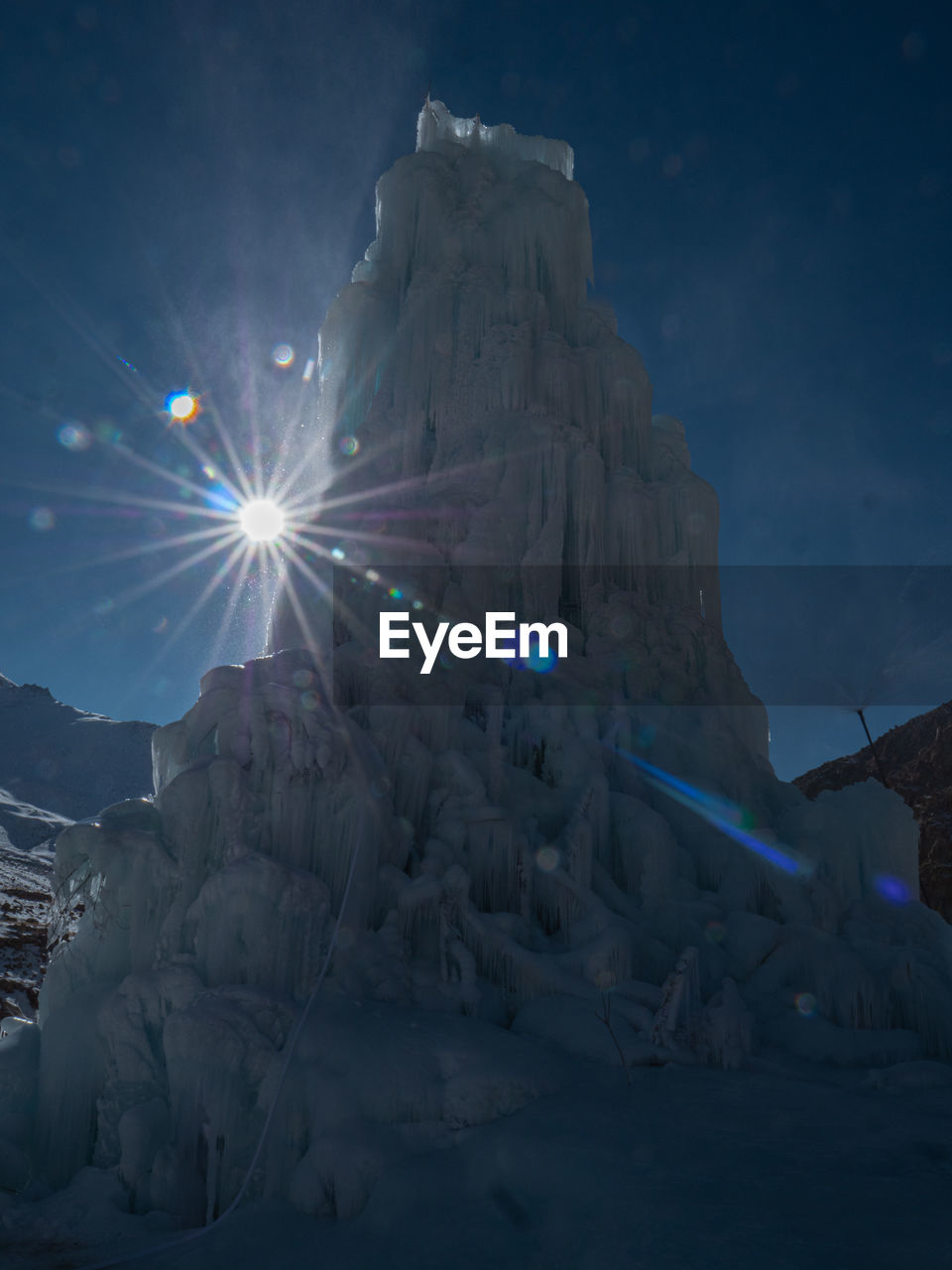 LOW ANGLE VIEW OF ILLUMINATED ICE AGAINST SKY