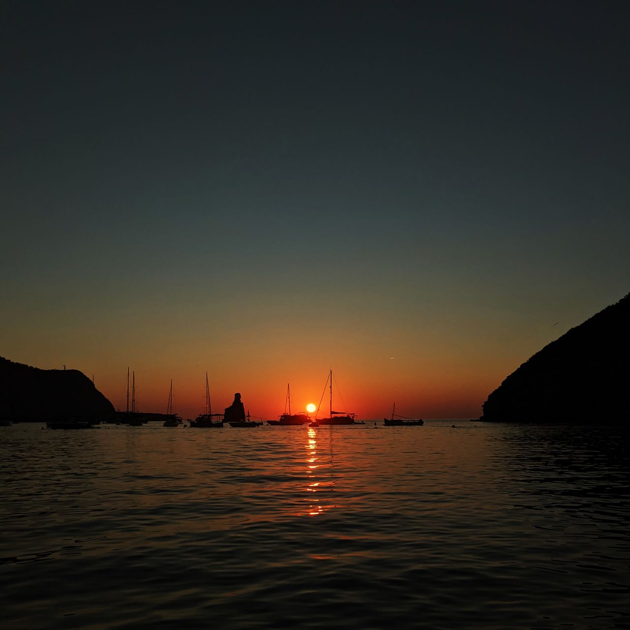 SILHOUETTE SAILBOATS IN SEA AGAINST SKY AT SUNSET