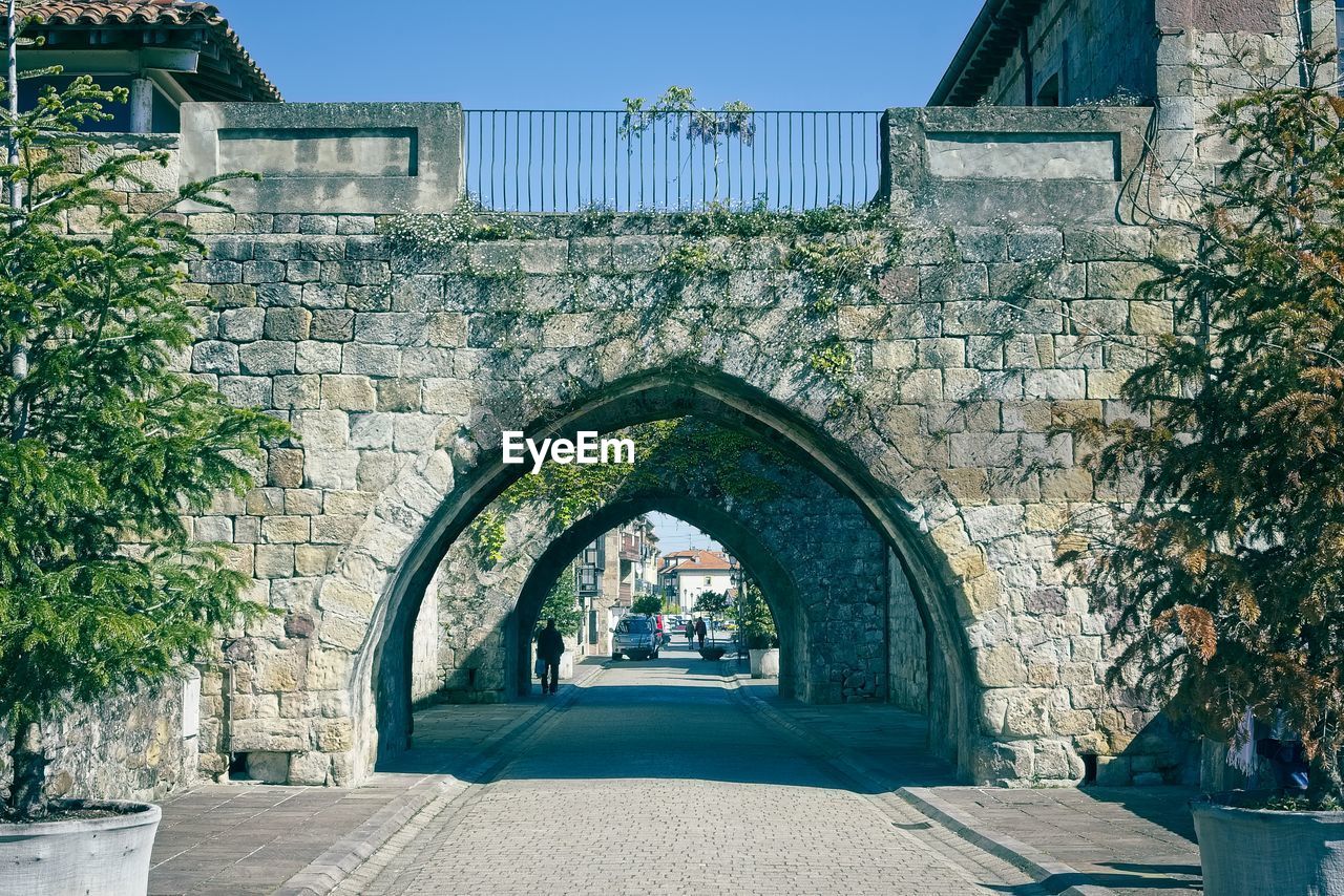 ARCH BRIDGE AMIDST BUILDINGS AGAINST SKY