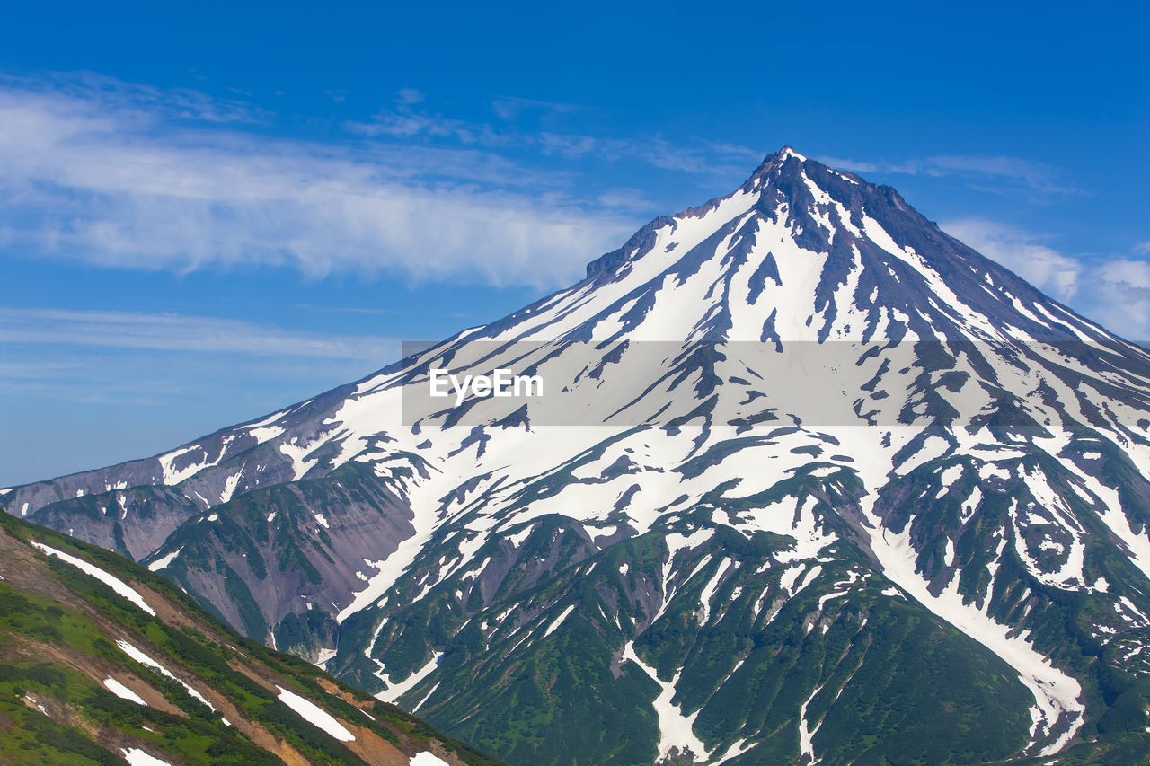 Volcano viluchinsky covered with snow at sunny summer day, the kamchatka peninsula.