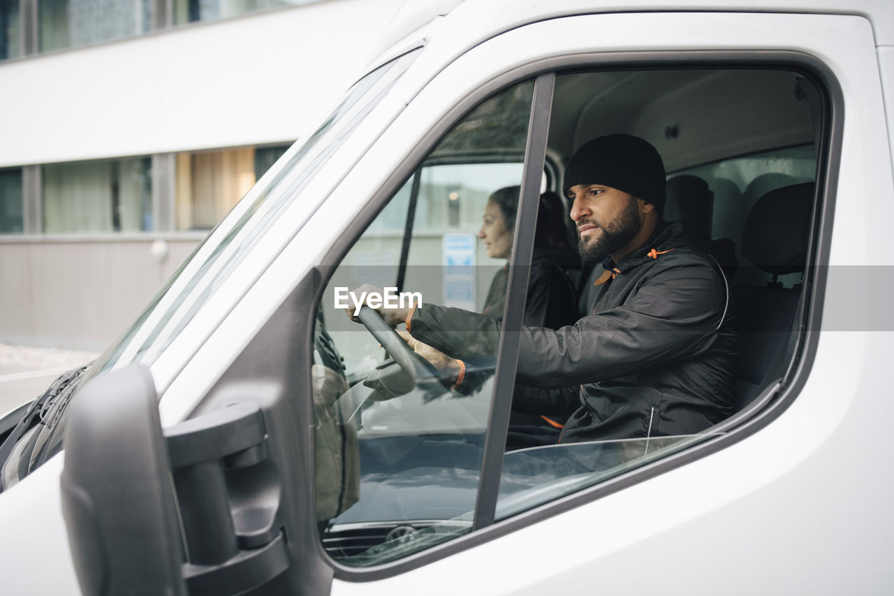 Male and female workers sitting in delivery van at city