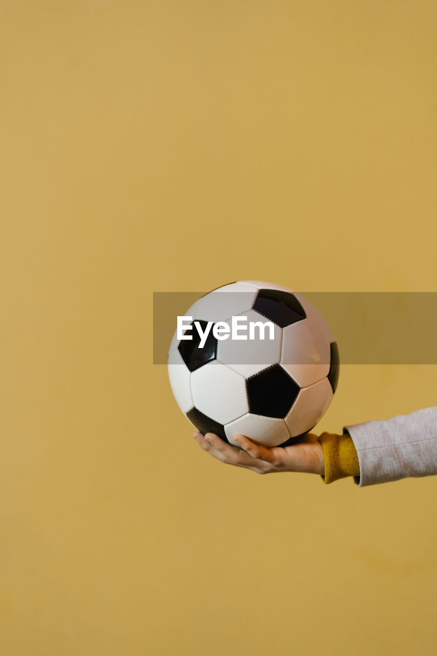 Man holding football against yellow wall