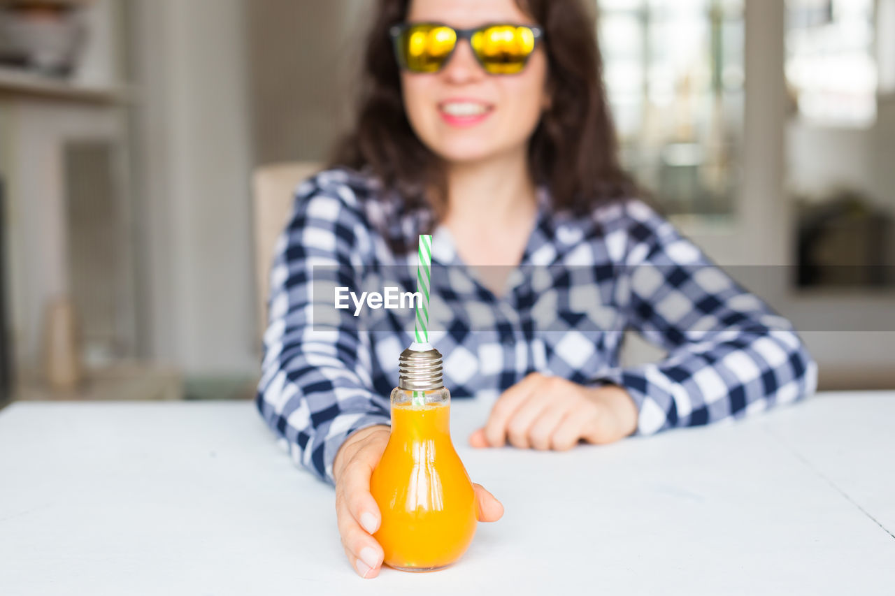 PORTRAIT OF YOUNG WOMAN HOLDING BOTTLE WITH TEXT