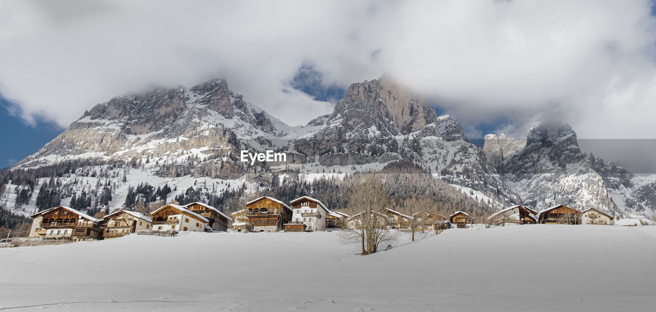 Panoramic view of snowcapped mountains and village against sky