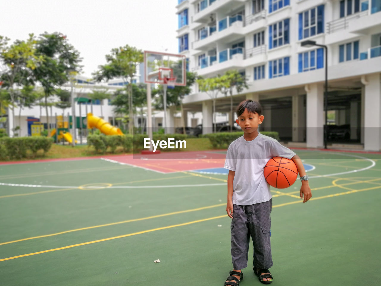 Full length of boy holding basketball at court