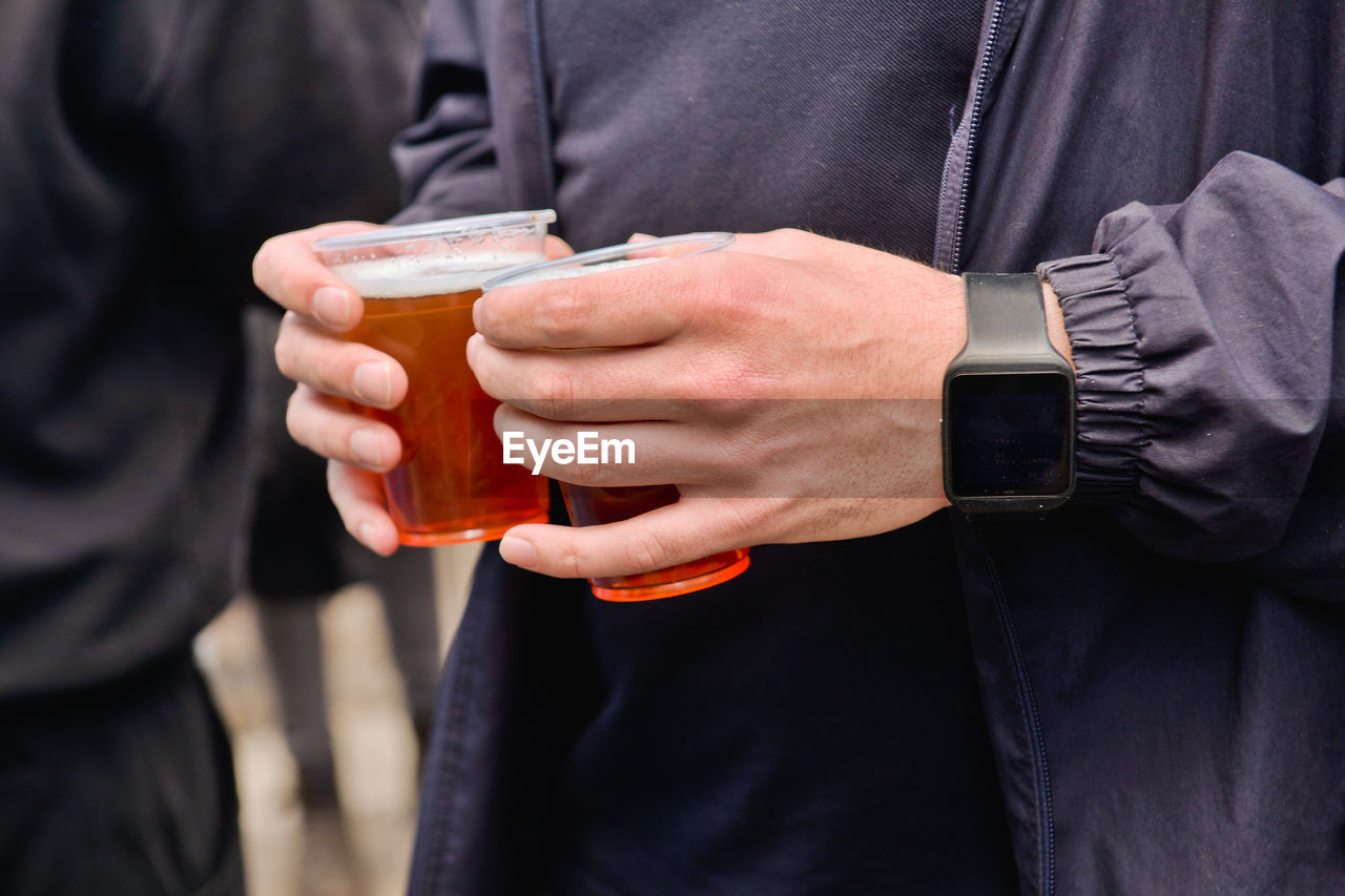 Midsection of man holding beer